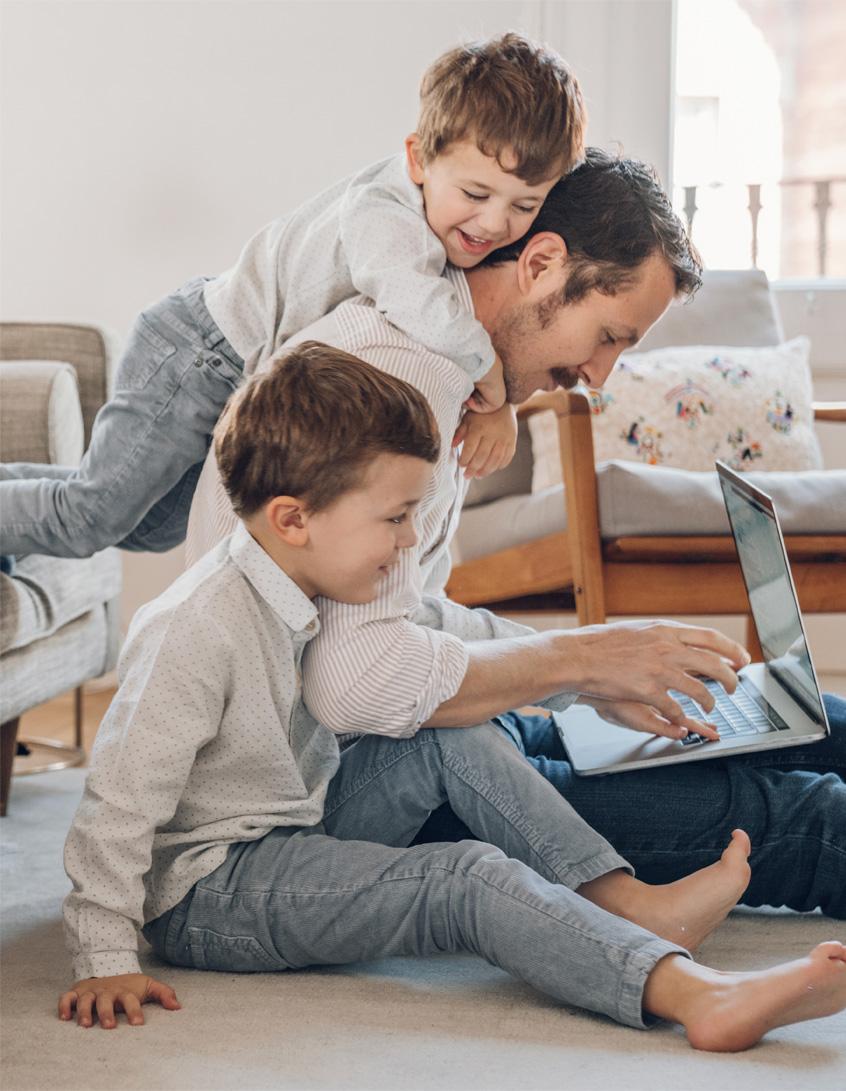 Padre manejando un ordenador portátil junto a sus dos hijos
