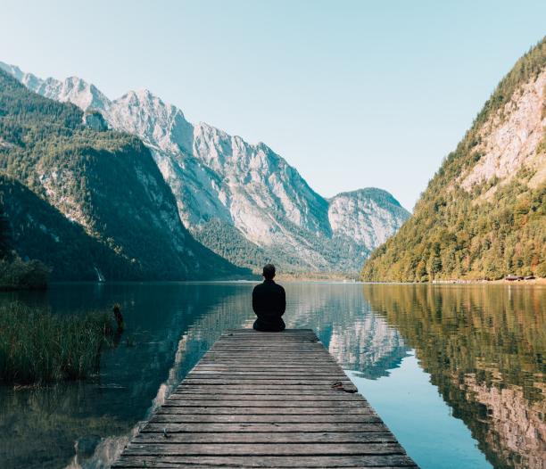 Person contemplating a lake in the mountains