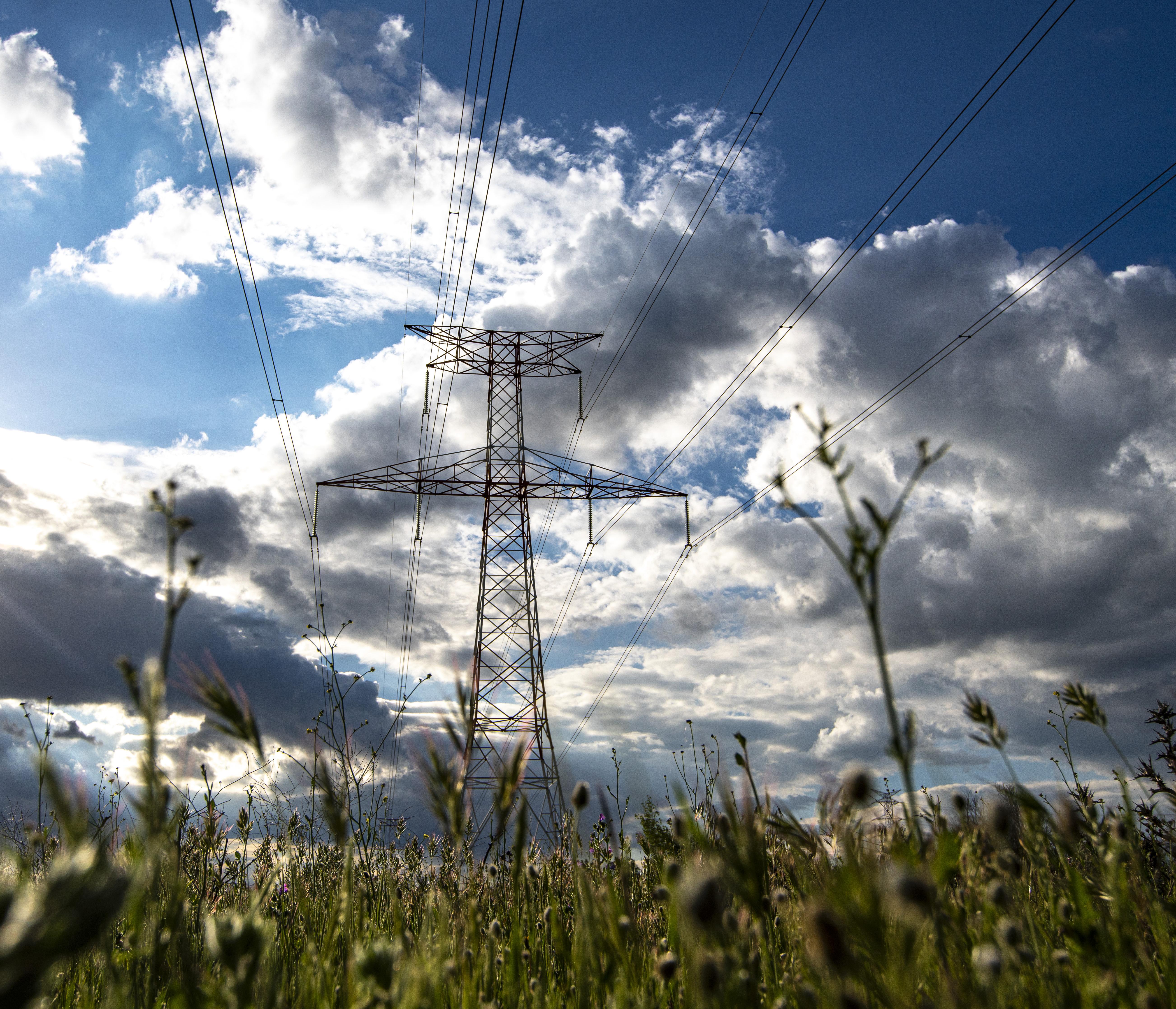 Torre eléctrica en un campo con el cielo de fondo nublado