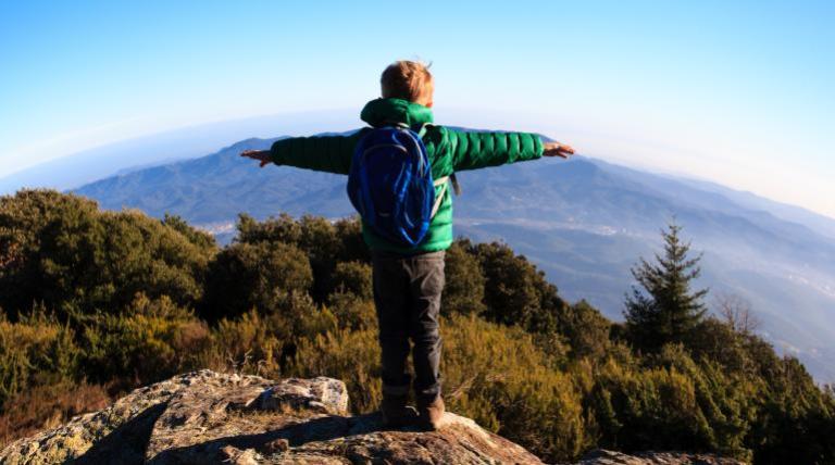 Child on a hill with arms crossed looking at the horizon