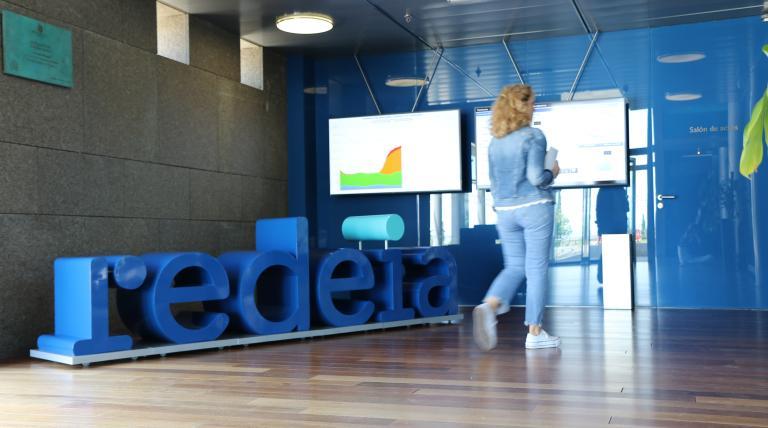 persona pasa caminando por delante de cartel de redeia en sus oficinas