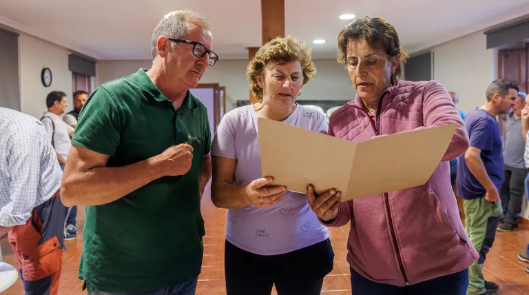 Dos ganaderas leyendo el convenio de colaboración, un momento antes de la firma, junto a Ramiro Palacios, de Agrovidar.